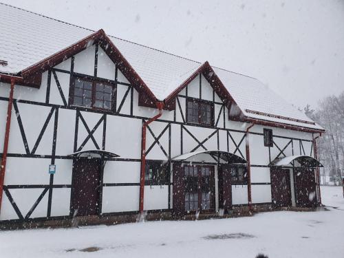 a black and white building covered in snow at Zirgu sēta "Klajumi" - Horse ranch "Klajumi" in Kaplava
