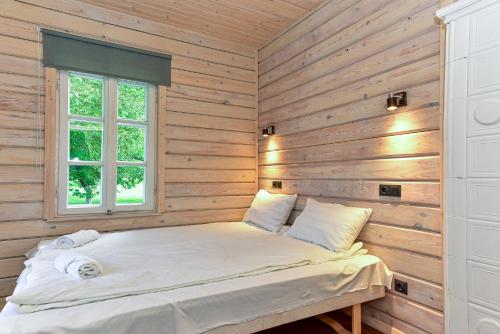 a bed in a room with wooden walls at Namelis ant ežero kranto "Mėlynas namelis" in Tytuvėnai