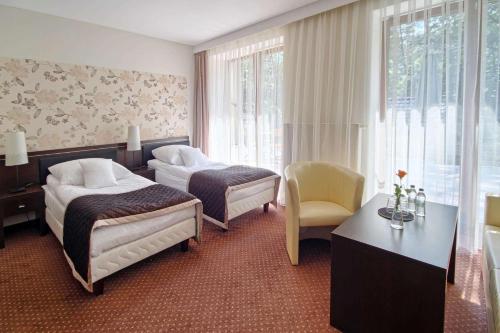 una camera d'albergo con due letti e un tavolo di Hotel Zacisze a Turawa