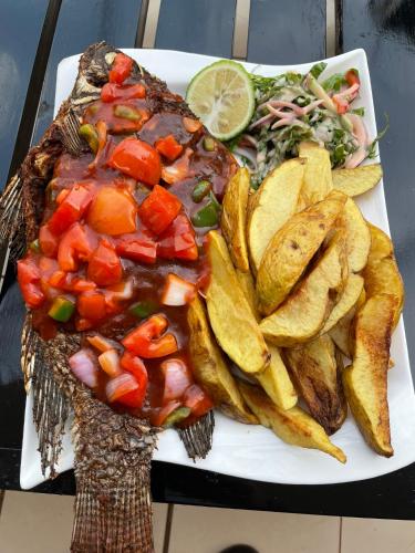 a plate of food with meat and chips and a salad at Sky Beach Hotel in Wakiso