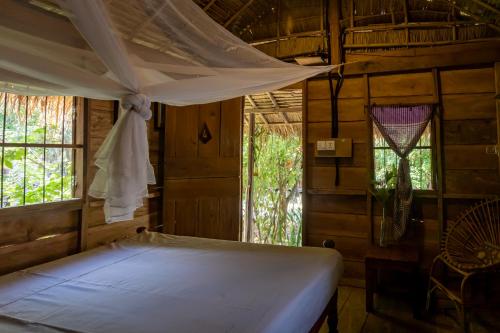 ein Schlafzimmer mit einem Bett in einem Zimmer mit Fenstern in der Unterkunft Kampot Cabana in Kampot