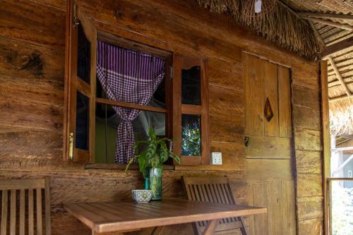 a wooden cabin with a table and a window at Kampot Cabana in Kampot