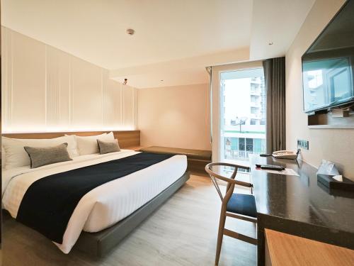 een slaapkamer met een bed, een bureau en een televisie bij Citrus Sukhumvit 13 Nana Bangkok by Compass Hospitality in Bangkok