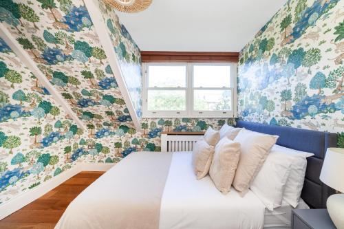 a bedroom with a white bed with floral wallpaper at The South Hampstead Collection in London
