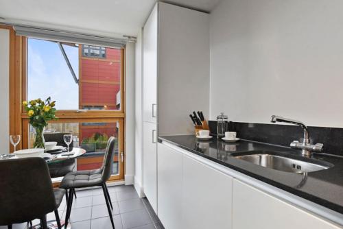 a kitchen with a sink and a table with chairs at Cubo Canary Wharf in London