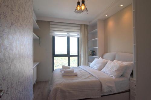1 dormitorio con 1 cama con ventana y lámpara de araña en Charming 3bdr Apartment For A Memorable Stay, en Basaksehir