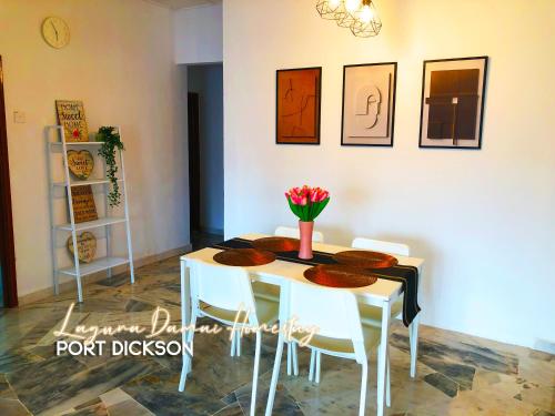 a dining room table with white chairs and flowers on it at Laguna Damai Homestay Teluk Kemang PortDickson 3BR in Port Dickson