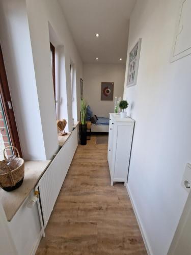 un pasillo de una casa con paredes blancas y suelo de madera en 1 Bedroom im Zentrum, en Schleswig