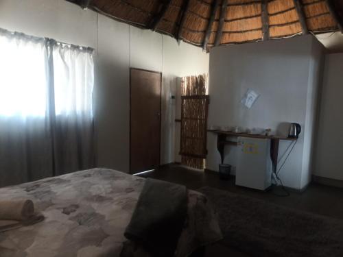 a bedroom with a bed and a table and a window at Mpora River Lodge in Rundu
