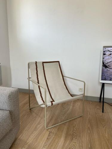 a chair sitting in a living room next to a couch at Maison Lumière - Appart. T2 architecte intra-muros in Avignon