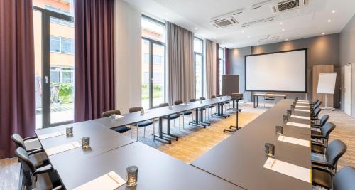 a large conference room with tables and chairs and a screen at PLAZA Premium München in Munich