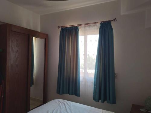 a bedroom with a window with blue curtains at British style in Makadi Heights in Hurghada