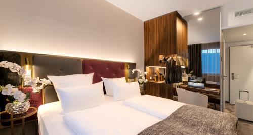 a bedroom with a large white bed and a desk at PLAZA Premium München in Munich