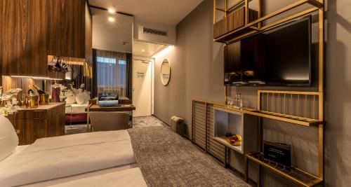 Habitación de hotel con cama, escritorio y TV. en PLAZA Premium München, en Múnich