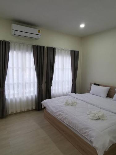 a bedroom with two beds and a window with curtains at NST Boutique เอ็นเอสทีบูทีค in Ban Pak Phun