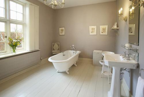 een badkamer met een bad, 2 wastafels en een raam bij The Old Rectory - Norfolk in North Tuddenham
