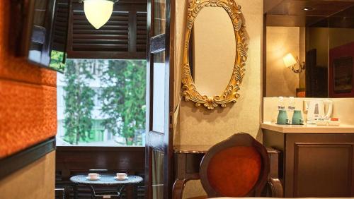 ein Badezimmer mit einem Spiegel und einem Stuhl neben einem Fenster in der Unterkunft Nostalgia Hotel in Singapur