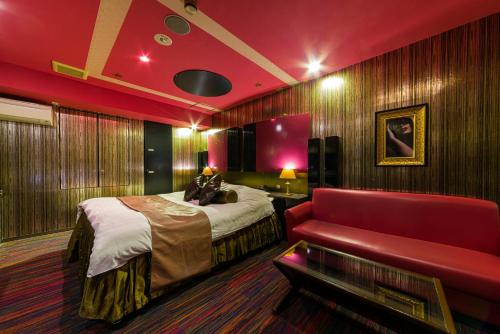 Habitación de hotel con cama y sofá rojo en HOTEL LOVE IKUTAMA -Adult Only, en Osaka