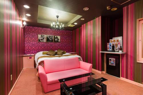 Dormitorio rosa con cama y silla rosa en HOTEL LOVE IKUTAMA -Adult Only, en Osaka