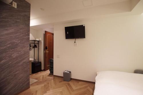a bedroom with a bed and a flat screen tv on the wall at MARUKOU HOTEL in Tokyo