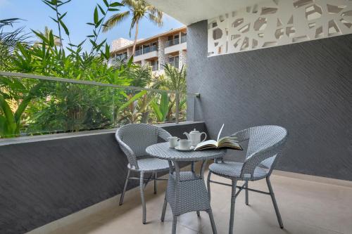a table and chairs with a book on a balcony at Hyatt Place Goa Candolim in Candolim
