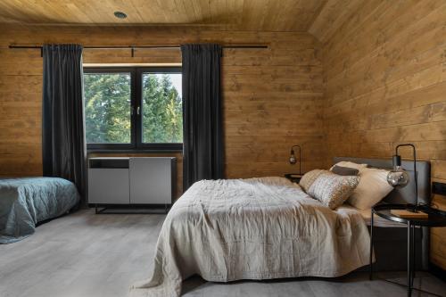 Schlafzimmer mit Holzwänden, einem Bett und einem Fenster in der Unterkunft Chillout nowoczesny dom w górach in Ślemień