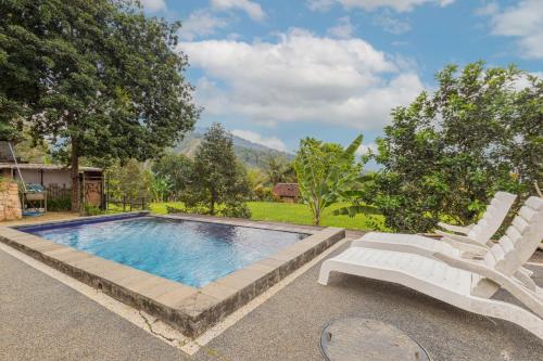 a swimming pool with two white chairs next to it at Mandhasativa Homestay in Singaraja
