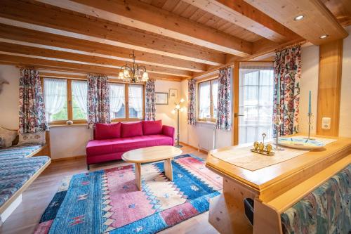 a living room with a pink couch and a table at Chalet Hildegard der Steinbock Sommerwohnung Winterferienhaus in Sankt Anton am Arlberg