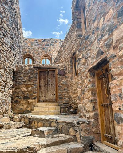 un antico edificio in pietra con porta e scale in legno di Hanging Terraces المدرجات المعلقة ad Al ‘Aqar