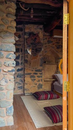 a room with a stone wall with pillows on the floor at Hanging Terraces المدرجات المعلقة in Al ‘Aqar