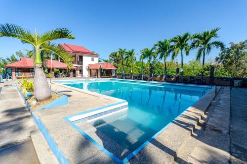 una piscina con una palmera junto a una casa en Magsaysay Hillside Resort powered by Cocotel, 