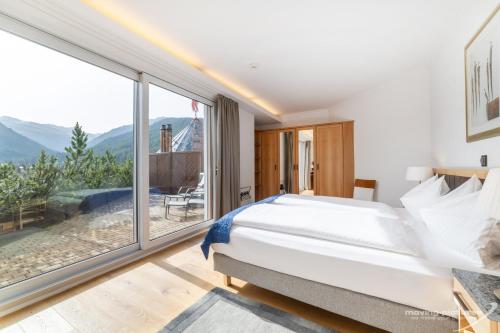 a bedroom with a bed and a large window at Swiss Quality Turmhotel Victoria in Davos