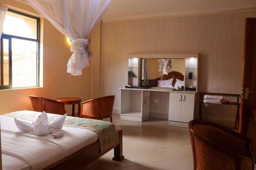 a bedroom with a bed and a table with chairs at Two Oceans Hotel Voi in Voi