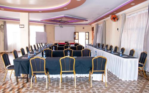 a conference room with tables and chairs and a screen at Two Oceans Hotel Voi in Voi