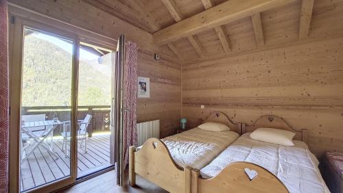a bed in a wooden room with a balcony at Chalet MON FRERE in Le Biot