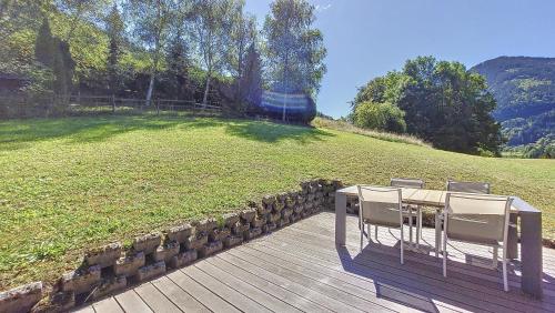 a wooden deck with a table and chairs on a field at Chalet MON FRERE in Le Biot