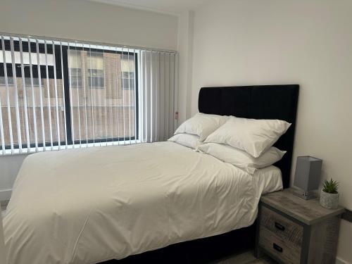 um quarto com uma cama com lençóis brancos e uma janela em Apartment In Luton Town Centre em Luton