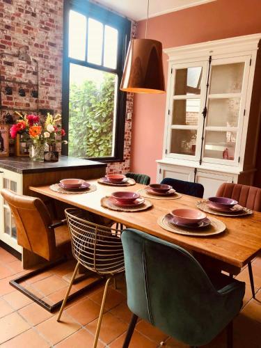 a kitchen with a wooden table with plates and chairs at Slapen bij de Brug in Zuidveld