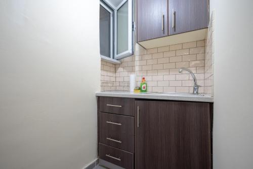 a kitchen with wooden cabinets and a sink at Pasalimani semi basement 2 persons flat by MPS in Piraeus