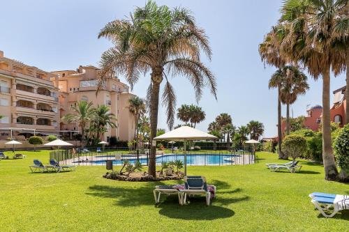 a resort with a pool and palm trees and chairs at Exclusive Alamos Beach in Torremolinos