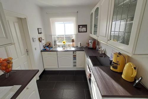 a kitchen with white cabinets and a sink and a window at Mawo Lodge in Lohfelden