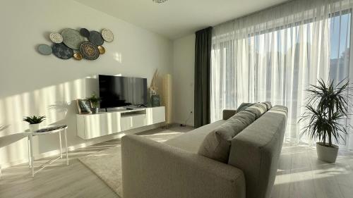 een woonkamer met een bank en een flatscreen-tv bij Linden Apartman 001 - Adults Only in Mosonmagyaróvár