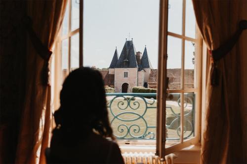 a woman looking out a window at a castle at Le château de Bonnemare - Bed and breakfast in Radepont