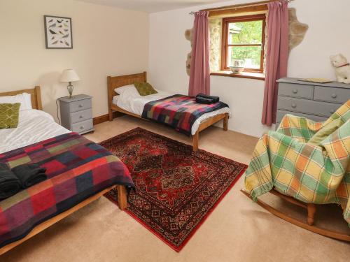 a bedroom with two beds and a rug at Y Beudy Garndeifog in Llanychaer