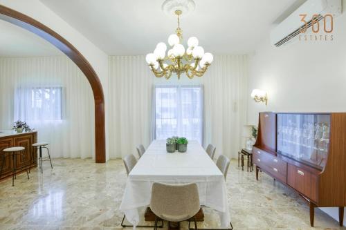 uma sala de jantar com uma mesa branca e um lustre em Spacious 4BR Oasis in the Heart of St. Julians by 360 Estates em St. Julian's