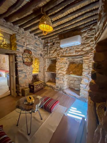 a living room with a table and a stone wall at Hanging Terraces المدرجات المعلقة in Al ‘Aqar