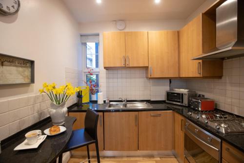 una cocina con armarios de madera y una mesa con flores amarillas. en Experience Vibrant Covent Garden - The Wanderlust by SmartStays en Londres