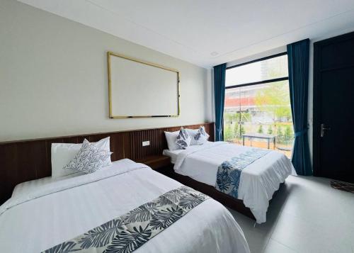 a hotel room with two beds and a window at Sandy Residence Sihanoukville in Sihanoukville