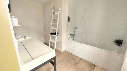La salle de bains est pourvue d'une baignoire blanche et d'un lavabo. dans l'établissement Appartement Bossoreil 110m2 - 3 chambres, à Angers