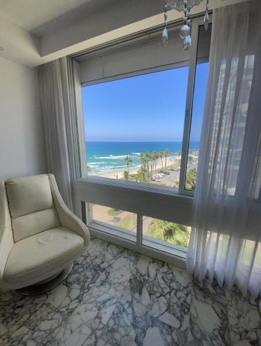 a room with a chair and a large window with the ocean at Star in Bat Yam